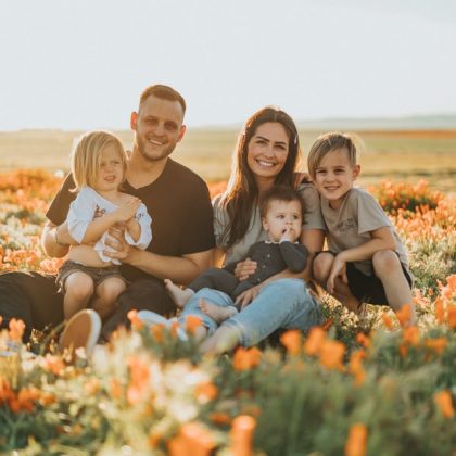 A family in a field of flowers, smiling at the camera